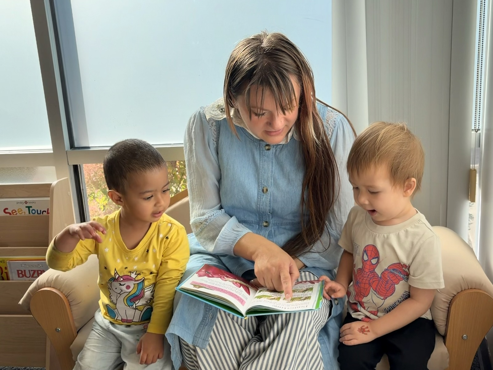 Ms. Nicole reading with two toddlers