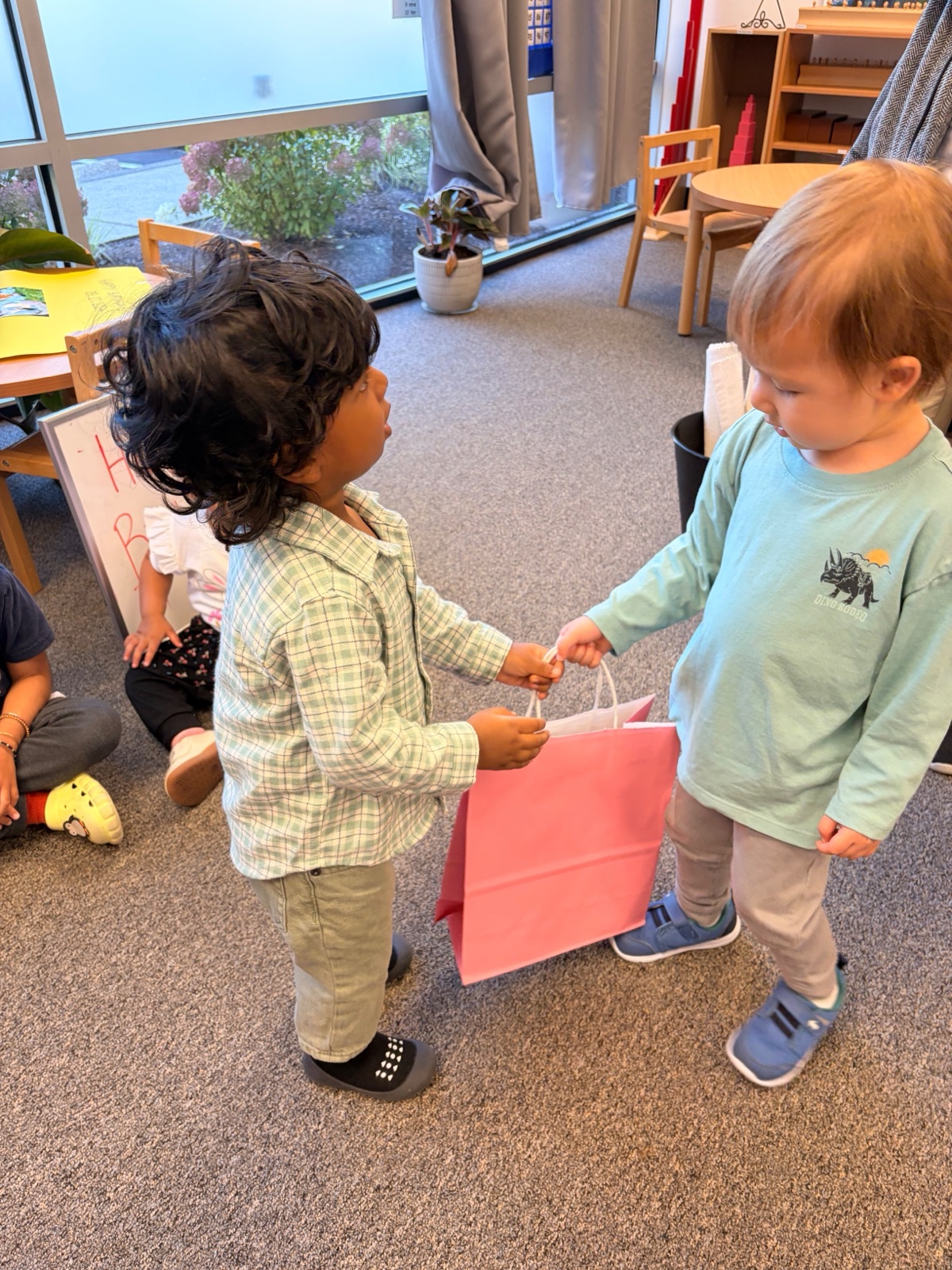 two toddlers handing a gift bag to each other